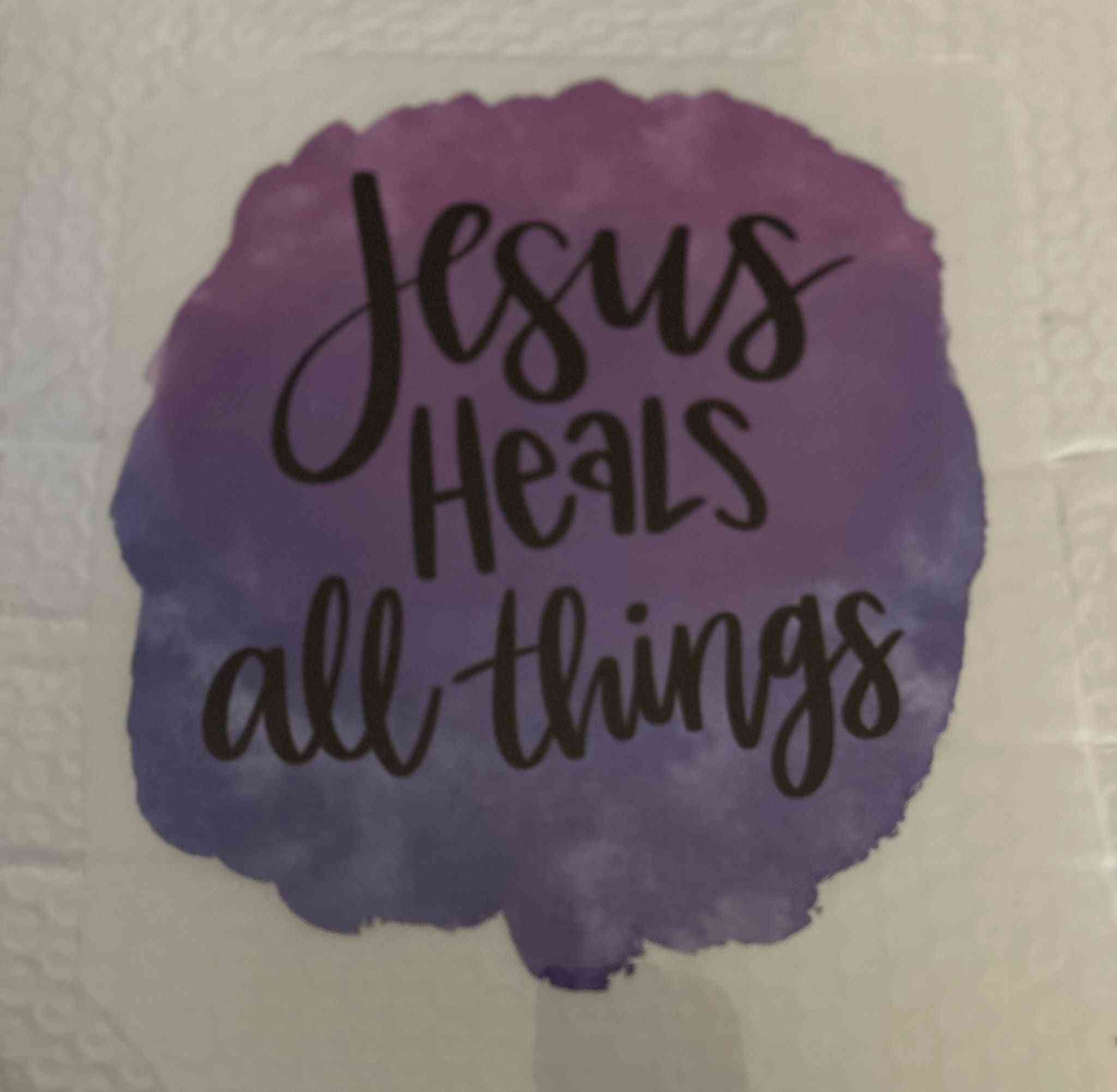 Purple watercolor patch with the text &quot;Jesus Heals all things&quot; in black, showcasing Sayings Design for personal expression.cute quote designs