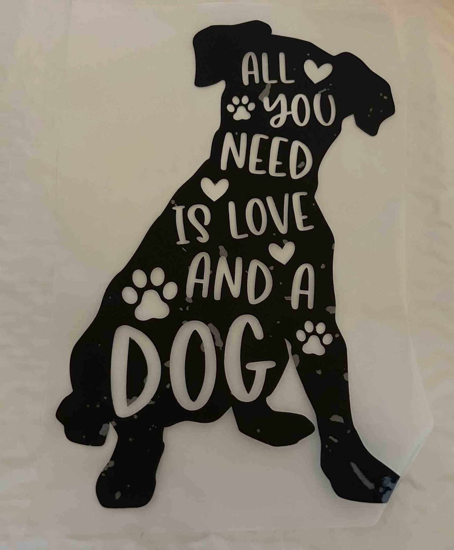 Silhouette of a dog with the phrase &quot;All you need is love and a dog&quot; featuring paw prints.