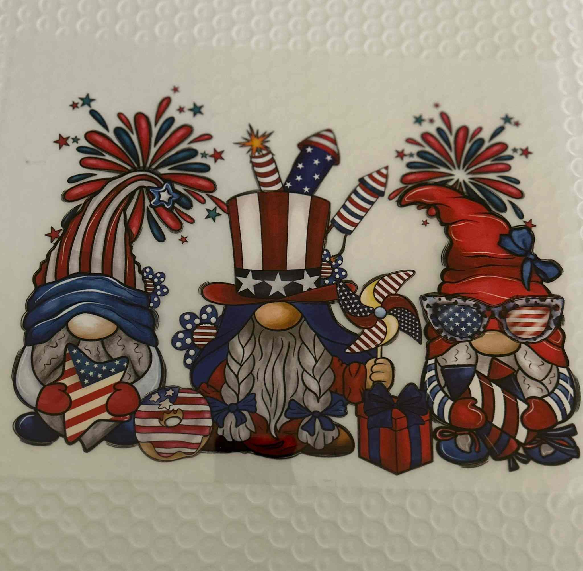 Patriotic design with gnomes in American flag outfits, featuring fireworks and stars.