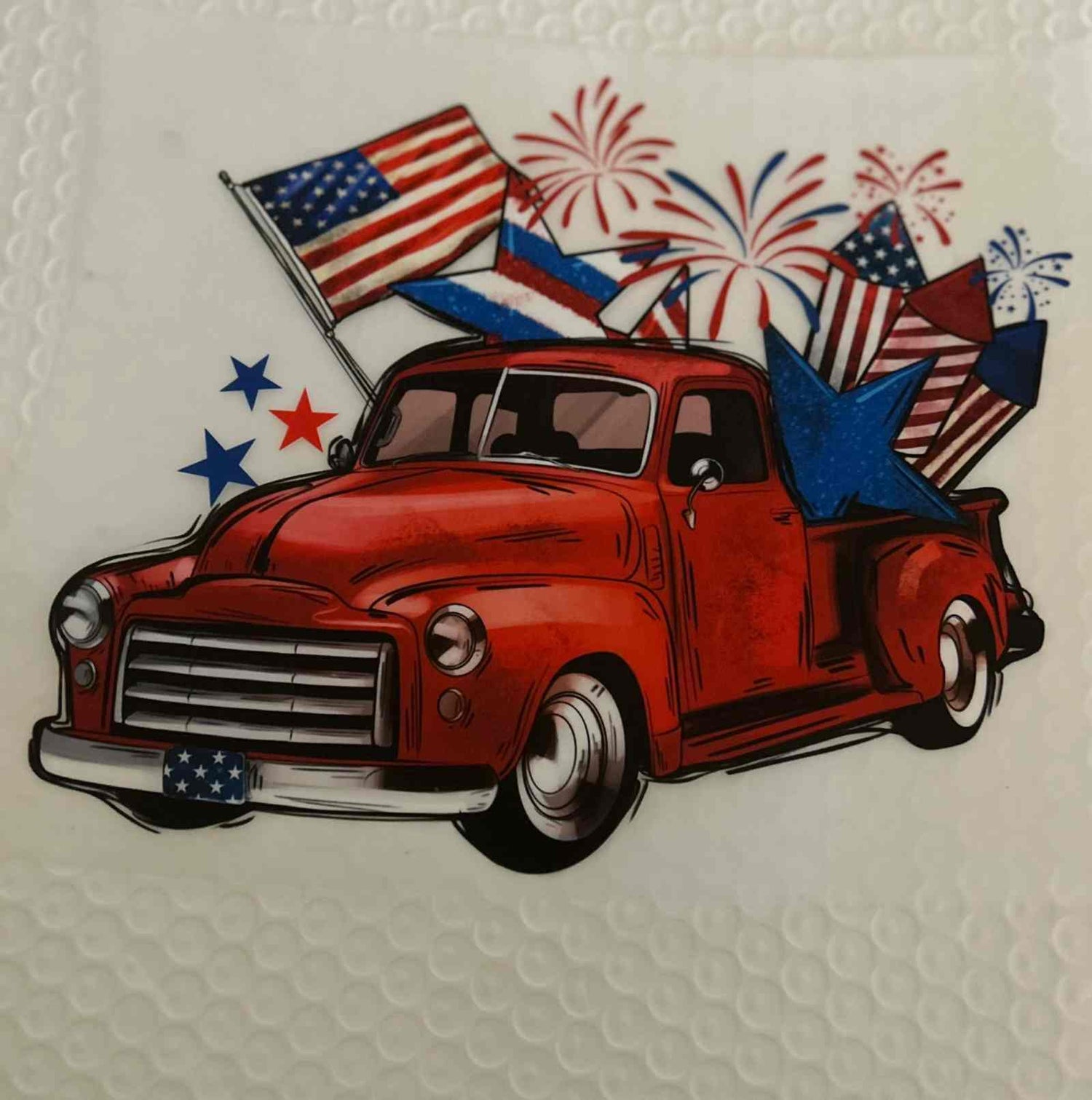 Red vintage truck with American flags, stars, and fireworks representing a patriotic design.