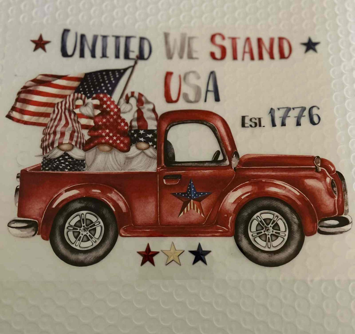 Patriotic design featuring a red vintage truck with American flags and &quot;United We Stand USA&quot; text.