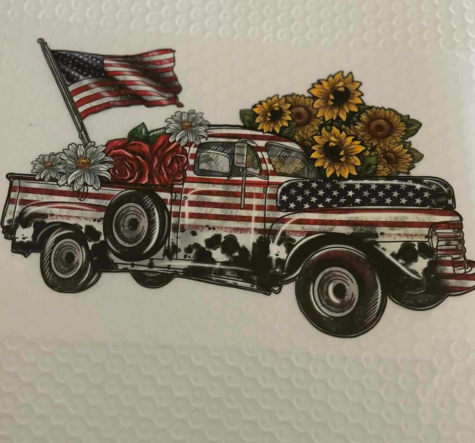 Vintage truck with American flag and flowers, featuring a patriotic design.