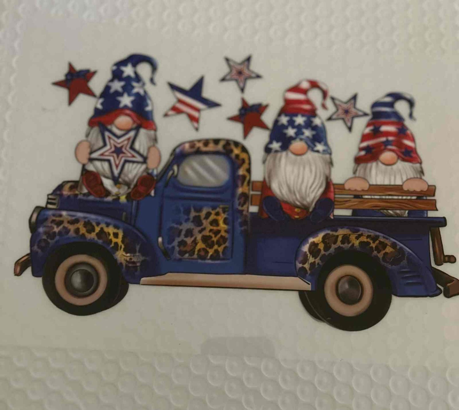 Patriotic design with gnomes in a vintage truck featuring American flag motifs and stars.