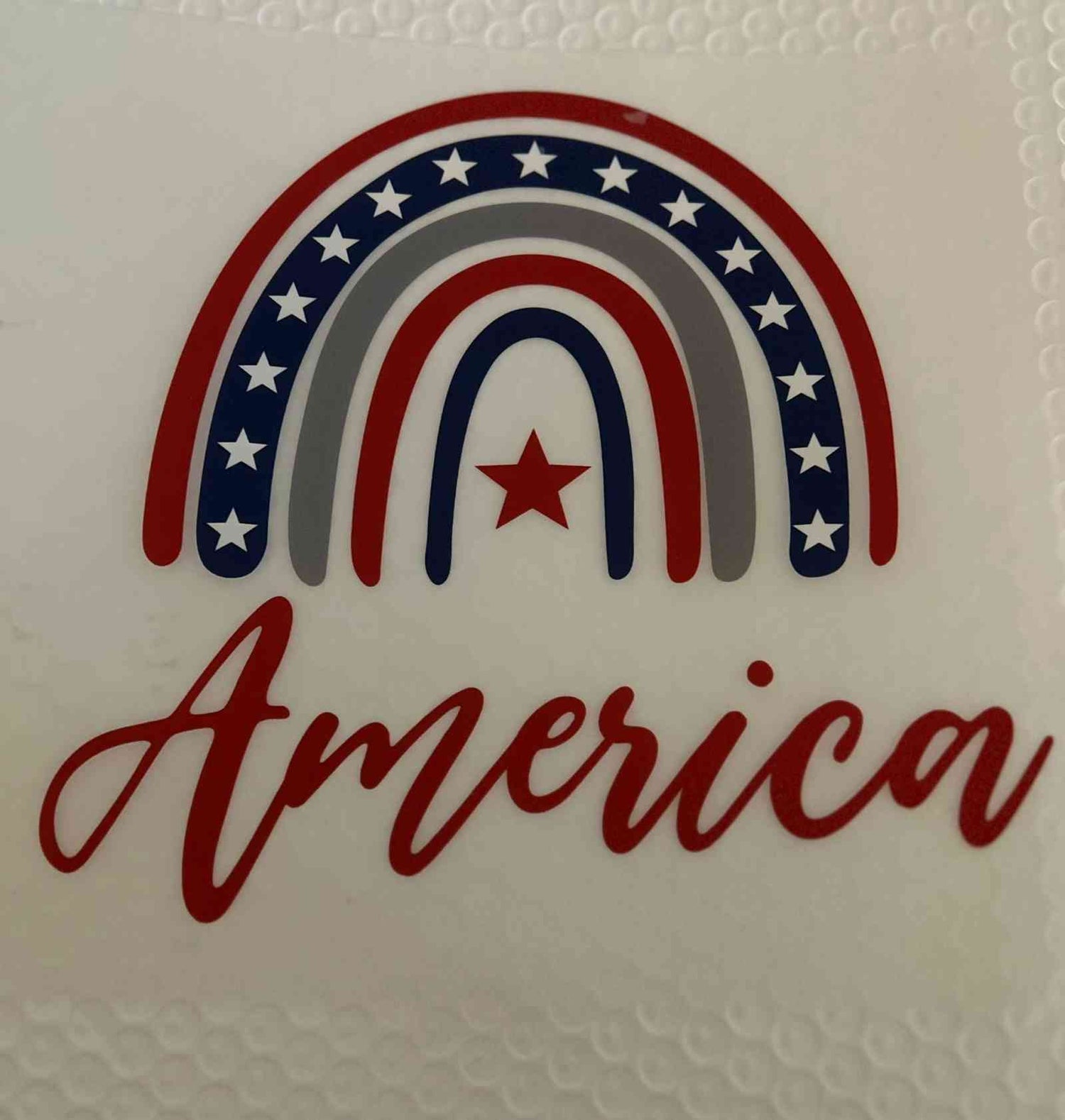 Patriotic design with American-themed rainbow and &quot;America&quot; text.