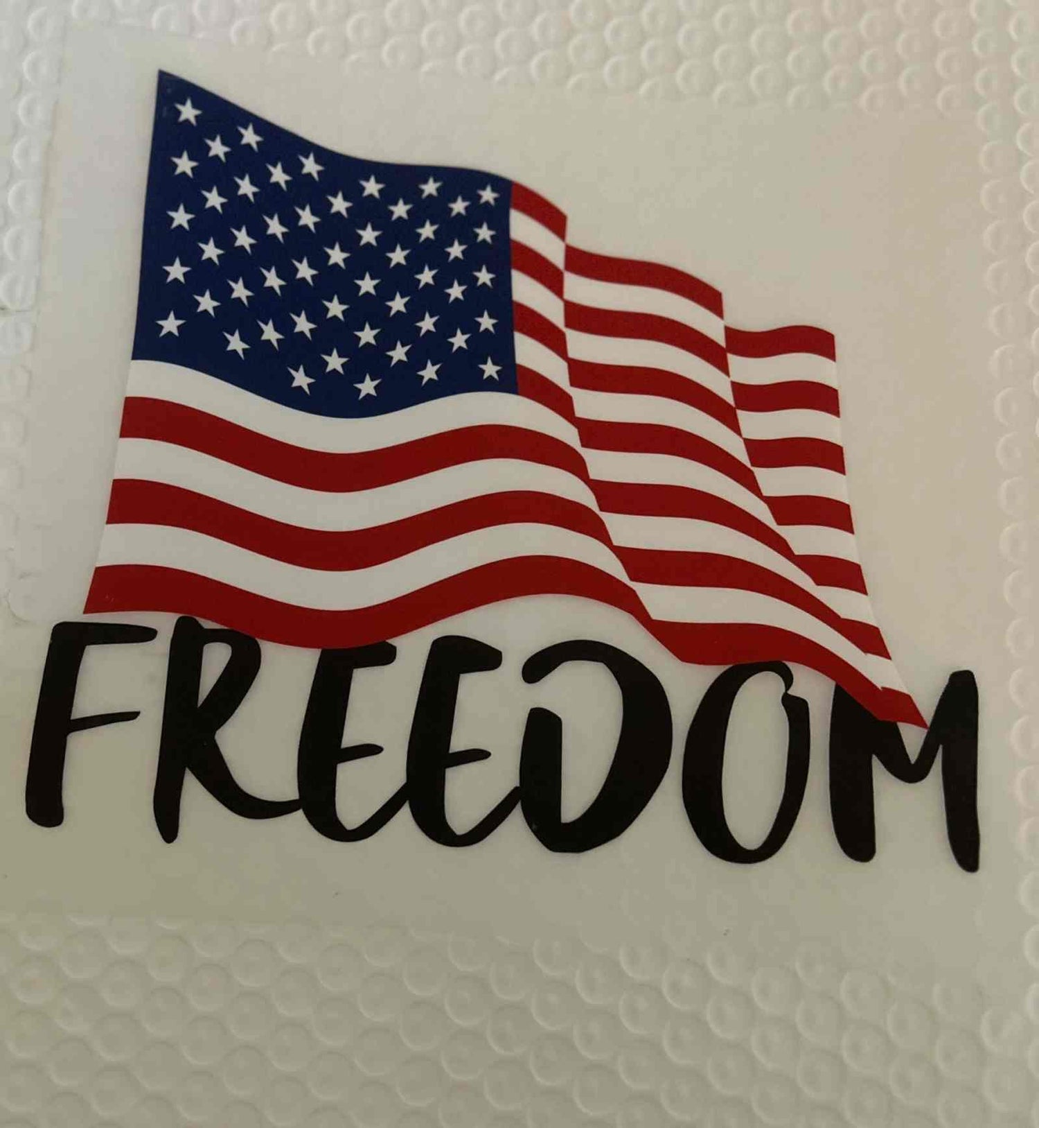 Patriotic design featuring a waving American flag with the word &quot;Freedom&quot;.