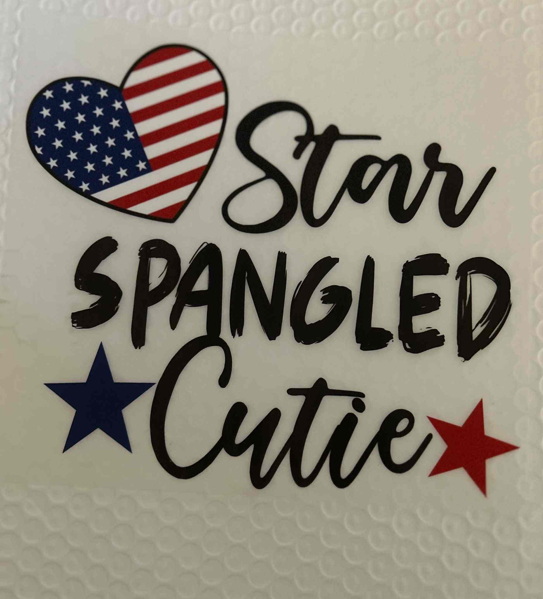 Heart-shaped American flag design with the words &quot;Star Spangled Cutie&quot; and two stars in a patriotic theme.