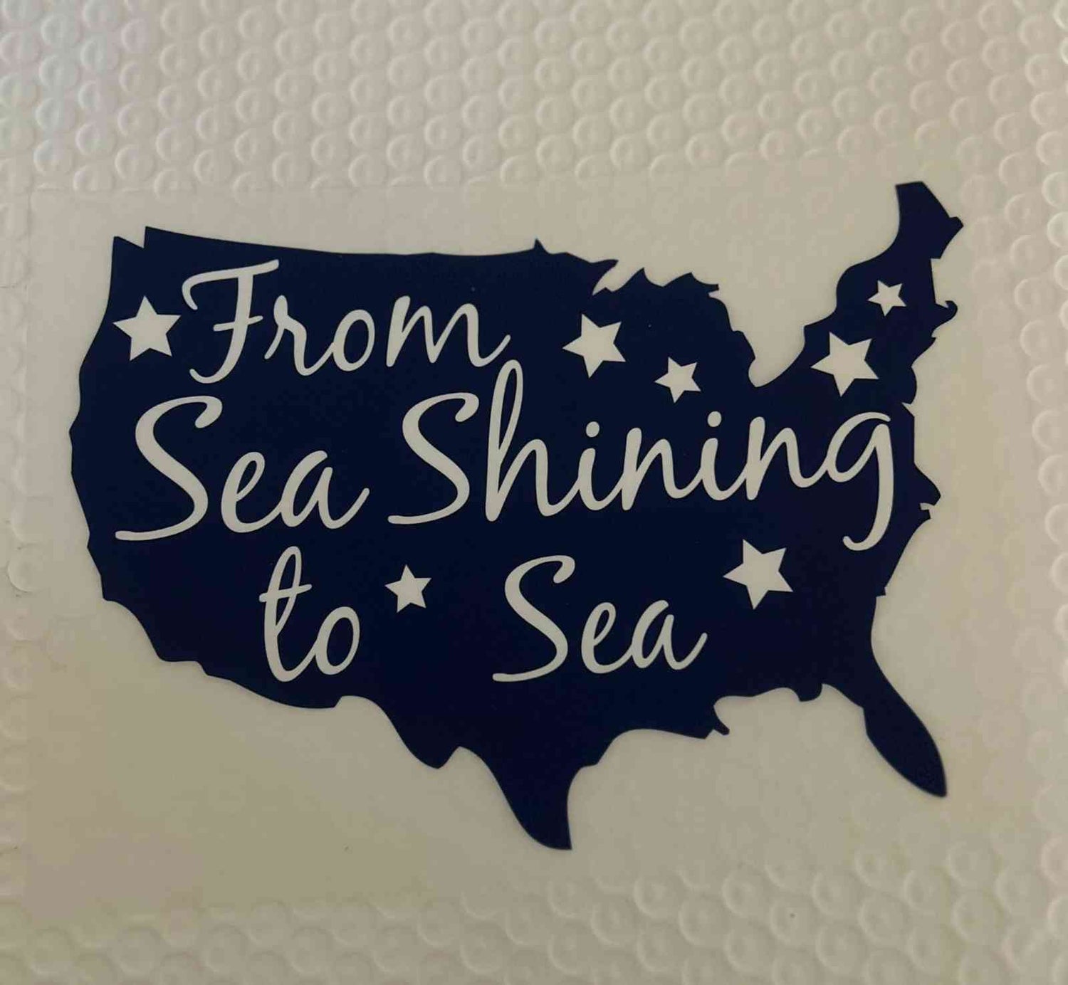 Silhouette of United States map with &quot;From Sea Shining to Sea&quot; text and stars, Patriotic Design.