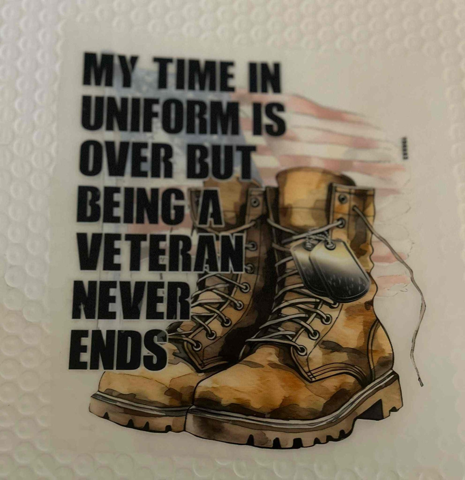 Patriotic design featuring combat boots and veteran quote with American flag background.